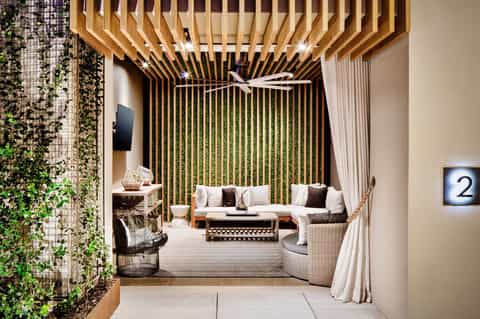 Modern lounge area with wooden slat ceiling, comfortable seating, and lush green plant wall