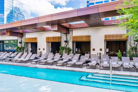 Modern resort pool with turquoise water, lounge chairs, and contemporary architecture with wooden accents