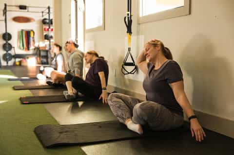 Group fitness class with women exercising on mats in bright studio with equipment wall