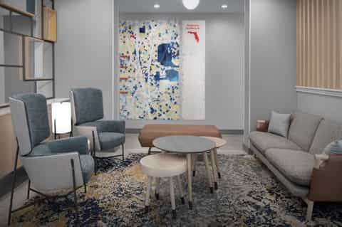 Modern lobby lounge with blue chairs, round table, and colorful wall art