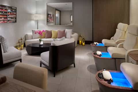 Luxurious spa relaxation room with plush seating, mirror, colorful pillows, and ambient lighting