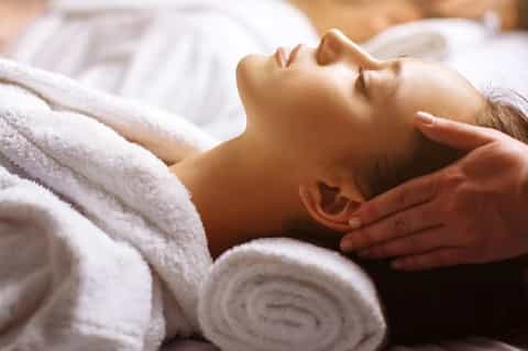 Spa massage therapy session with therapist performing head massage on relaxed client