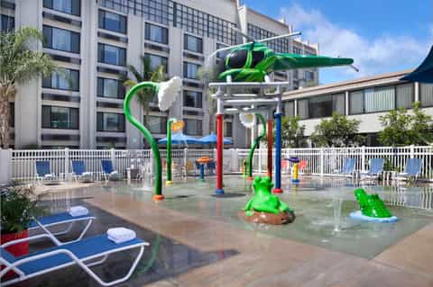 Splash pad with green airplane sculpture and water play features for children