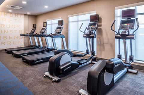 Fitness center with cardio equipment including treadmills and ellipticals with large windows