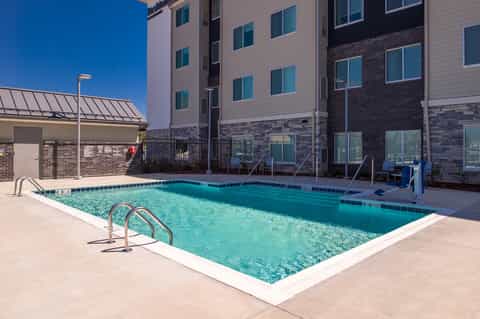 Outdoor swimming pool at hotel with turquoise water, metal railings, and multi-story brick building