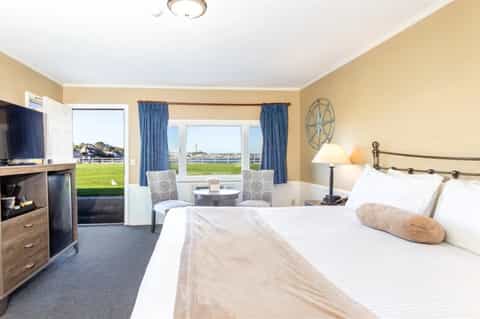 Spacious hotel room with queen bed, patio doors overlooking golf course, TV, and warm lighting