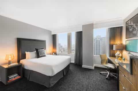 Upscale hotel room with city view, modern furnishings, and work desk