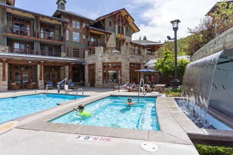 Rustic stone resort with hot tubs, pools, and waterfall feature surrounded by wooden architecture
