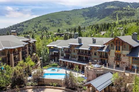 Mountain resort community with lodge buildings, heated pool, and forested slopes