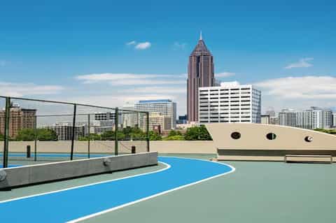 Rooftop basketball court with city skyline and tall building in background