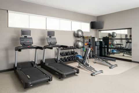 Fitness center with treadmills, dumbbells, exercise balls, and wall mirror