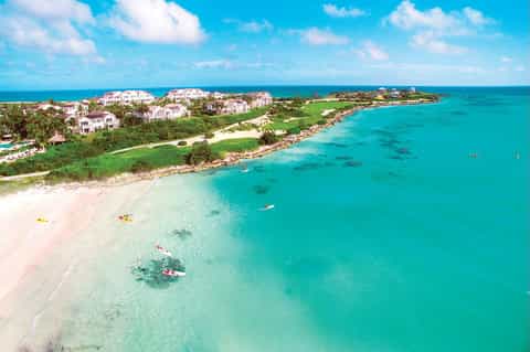 Aerial view of beachfront resort with turquoise waters, pink sand beach, and oceanfront homes