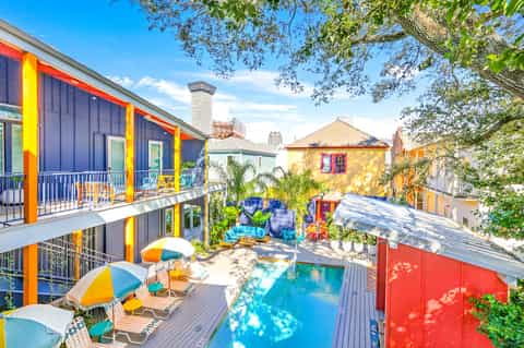Vibrant colorful hotel courtyard with bright blue and yellow architecture, small pool, and umbrellas