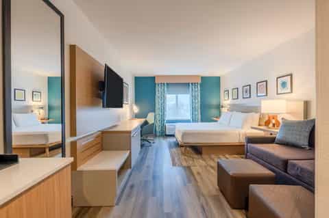 Modern hotel room with teal accent walls, dual beds, desk, and contemporary furnishings