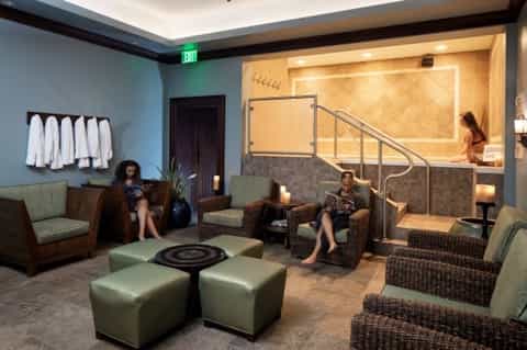 Spa lounge area with light blue walls, wicker chairs, hot tub, and relaxation seating