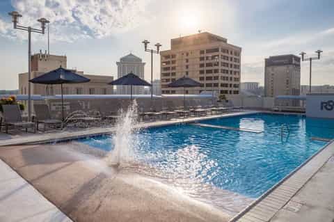 Modern rooftop pool with city skyline views, lounge chairs, and umbrellas