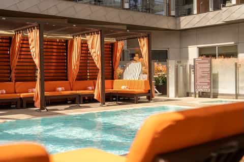 Indoor pool with orange cabanas, striped cushions, and modern building architecture