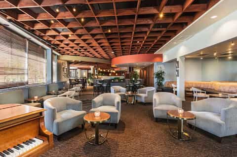 Elegant hotel lobby lounge with wooden ceiling, piano, comfortable seating, and modern decor