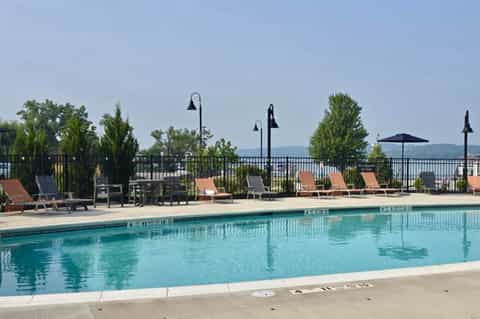 Lakeside pool deck with lounge chairs, umbrellas, black railings, and mountain backdrop