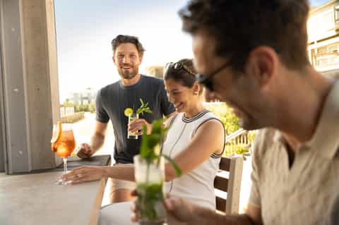 Social gathering on resort terrace with guests enjoying cocktails and conversation during golden hour