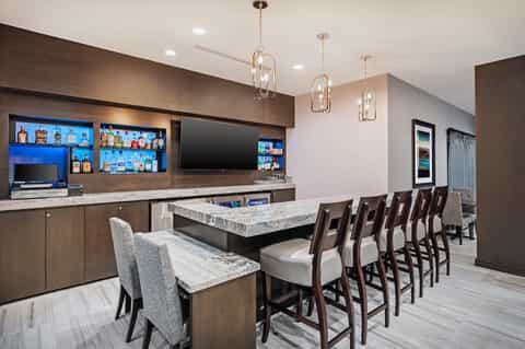 Game room with bar counter, hanging pendant lights, and high seating overlooking patio area