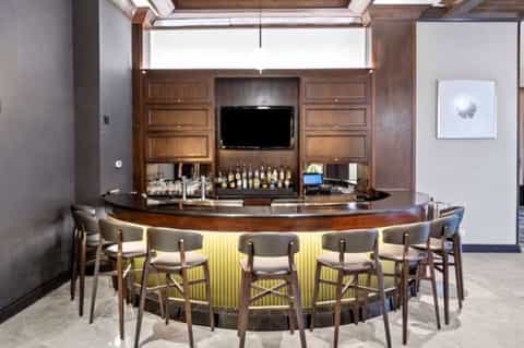 Contemporary curved bar with wood cabinetry, LED lighting, and upholstered seating
