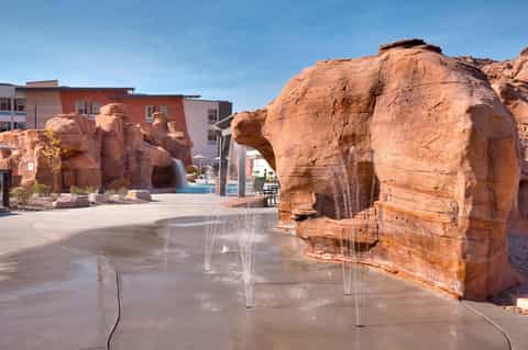 Resort courtyard with red rock formations, water fountain feature, and hotel building