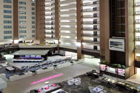 Multi-story hotel atrium with modern architecture, neon lighting, and ground-level lounge seating