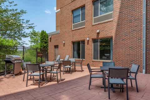 Brick patio with dark metal chairs and tables overlooking green landscaping