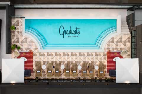 Hotel event space with turquoise ceiling signage reading 'Graduate Tucson' and geometric floor pattern