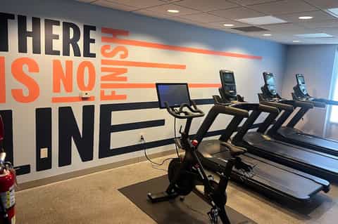 Fitness center with exercise bikes and treadmills against motivational wall mural