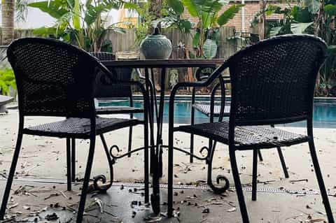 Black patio chairs and table overlooking a small residential pool area