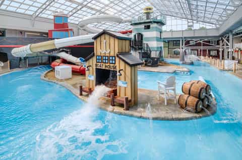 Indoor water park with boat-themed play structures, slides, and shallow pools
