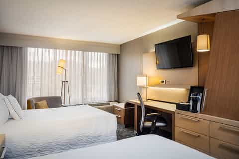 Hotel guest room with queen beds, desk, TV, and contemporary decor