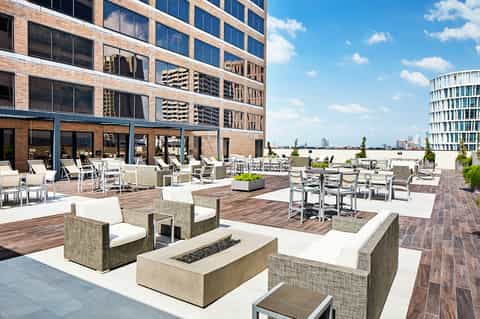 Modern rooftop terrace with contemporary furniture, fire pit, and city skyline views