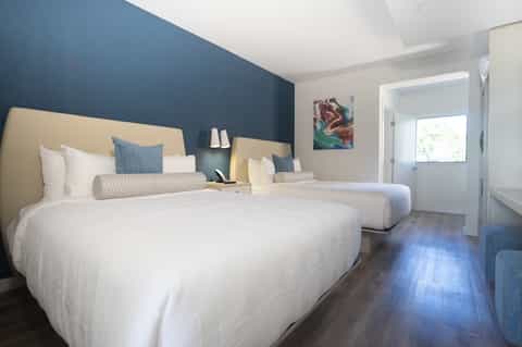 Hotel guest room with two queen beds, blue accent wall, and modern contemporary furnishings