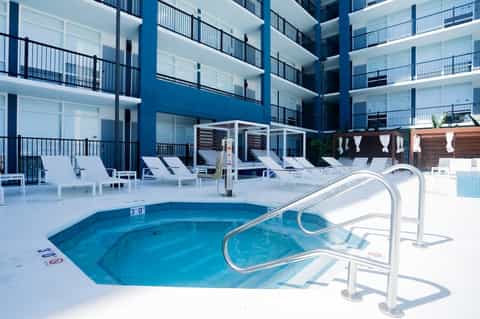 Hotel courtyard pool with blue water, white loungers, and multi-story blue building