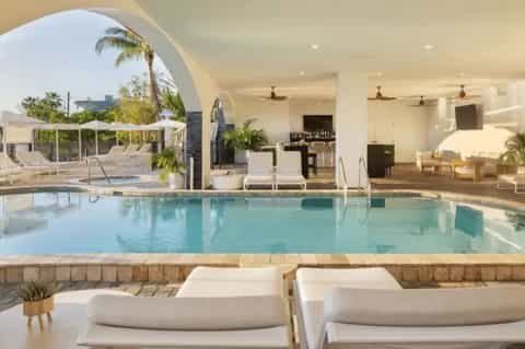 Indoor pool facility with arched architecture, lounge chairs, and palm plants