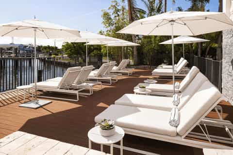 Waterfront lounge deck with cushioned loungers, umbrellas, and river views