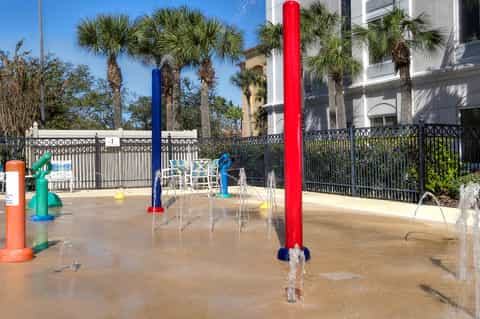 Resort splash pad for children with colorful water jets, fountains, and fencing