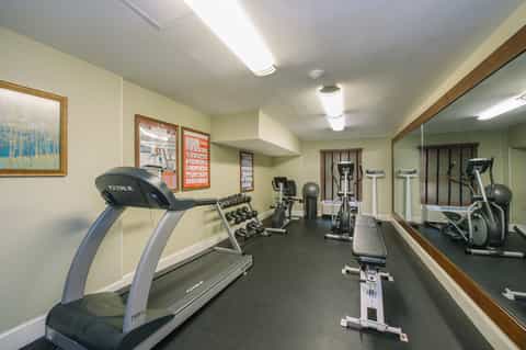 Fitness center with treadmills, free weights, exercise bikes, and mirrors