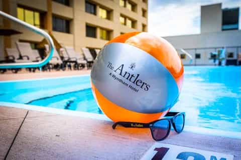 Beach pool at The Antlers hotel with branded beach ball, sunglasses, and lounge chairs