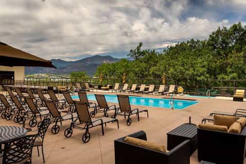 Resort pool area with lounge chairs, mountain views, and manicured landscaping