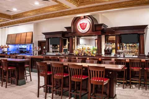 Upscale bar with dark wood cabinetry, extensive liquor selection, and red-cushioned seating