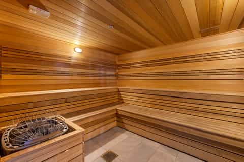 Wooden sauna interior with tiered benches and warm cedar paneling throughout