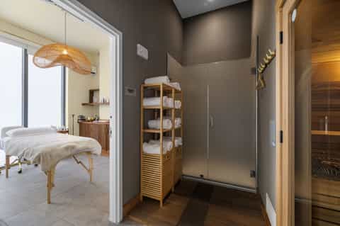 Spa bathroom with wooden sauna, rain shower, massage table, and amenities shelf