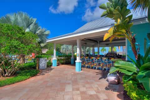 Tropical bar pavilion with turquoise columns, palm trees, and ocean view in background