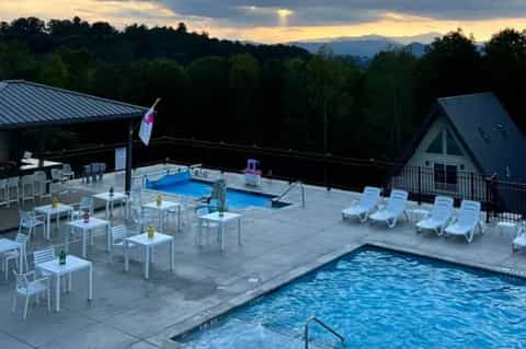 Mountain-view resort pool deck at dusk with loungers, gazebo, and scenic backdrop