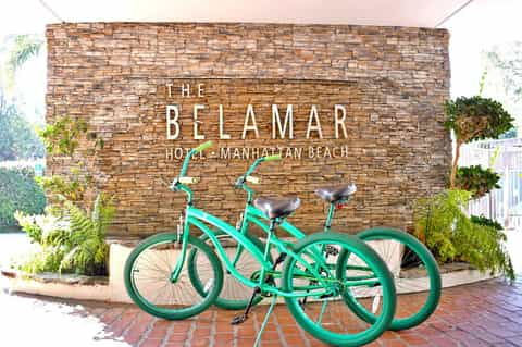 The Belamar Hotel Manhattan Beach sign with two teal bicycles in front