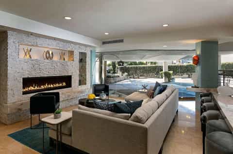 Modern resort lounge with fireplace, sectional seating, and pool view through glass doors